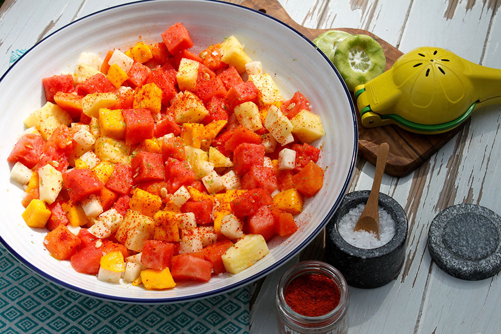 bowl of fruit salad with chile powder salt and lime